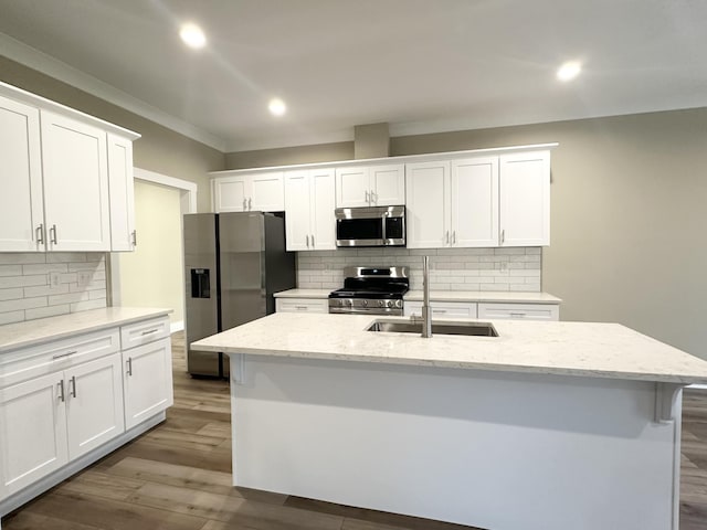 kitchen featuring hardwood / wood-style floors, a center island with sink, backsplash, appliances with stainless steel finishes, and white cabinetry