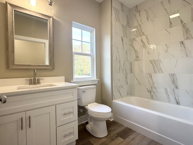 full bathroom featuring toilet, hardwood / wood-style floors, tiled shower / bath combo, and vanity