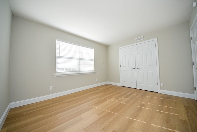 unfurnished bedroom with light hardwood / wood-style flooring and a closet