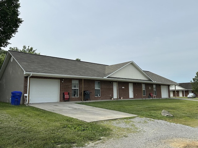 view of front of home featuring brick siding, a garage, driveway, and a front yard