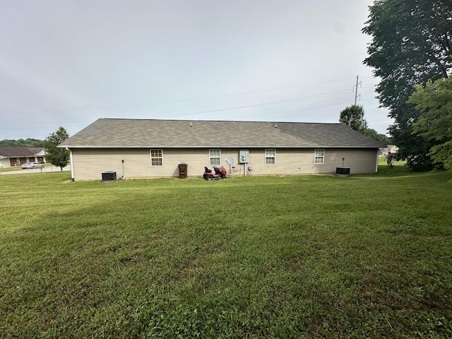rear view of property featuring central air condition unit and a yard
