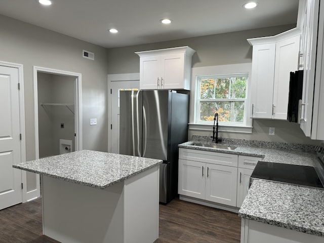 kitchen with white cabinetry, a center island, light stone countertops, and sink