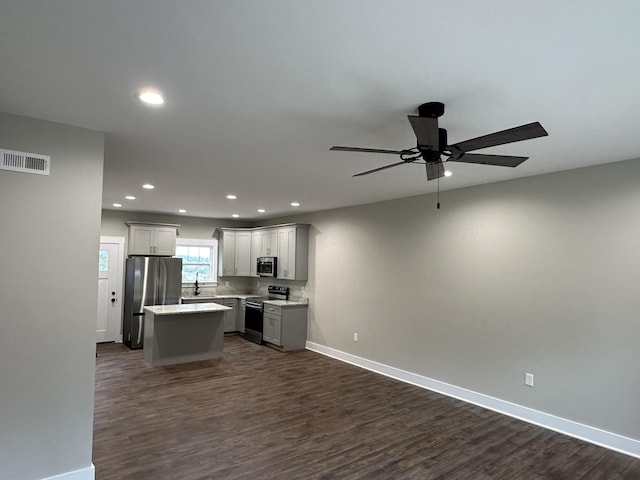 kitchen featuring dark hardwood / wood-style flooring, ceiling fan, a kitchen island, gray cabinets, and stainless steel appliances