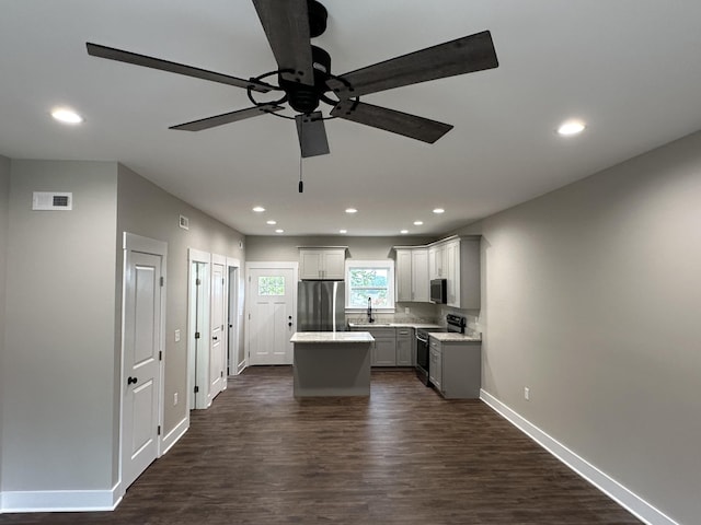 kitchen featuring gray cabinetry, appliances with stainless steel finishes, sink, a center island, and dark wood-type flooring