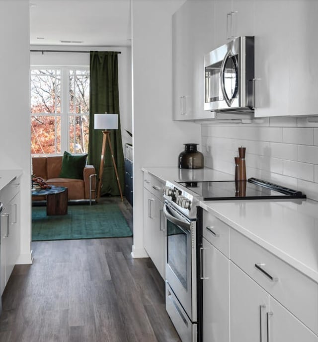 kitchen featuring backsplash, white cabinetry, dark hardwood / wood-style flooring, and stainless steel appliances