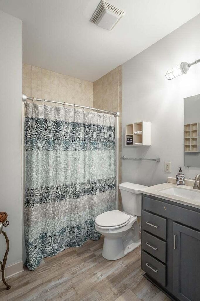 bathroom featuring curtained shower, hardwood / wood-style floors, vanity, and toilet