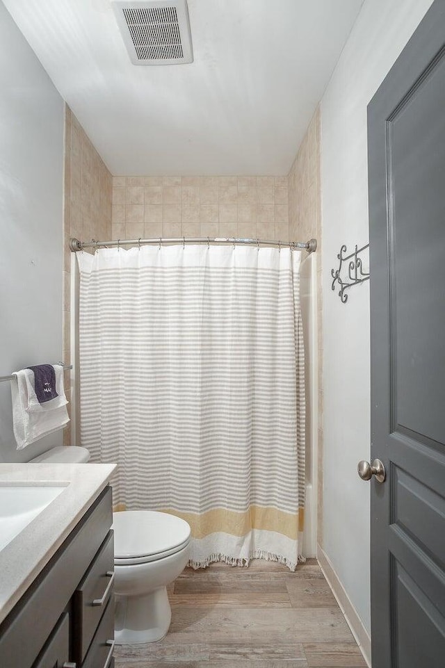 bathroom with hardwood / wood-style floors, vanity, toilet, and walk in shower