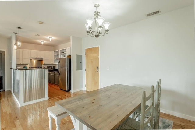 dining space with light hardwood / wood-style floors, electric panel, and a chandelier