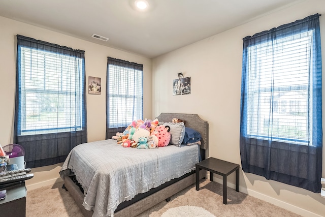 bedroom with multiple windows and light carpet