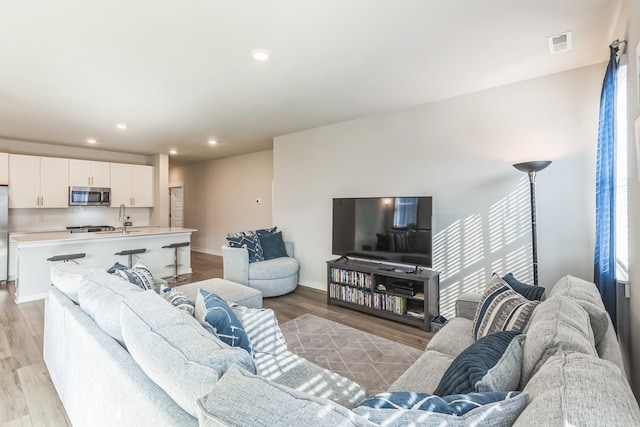 living room with light hardwood / wood-style flooring and sink