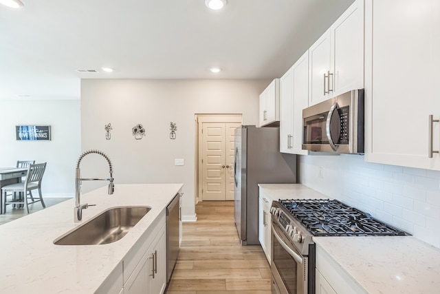 kitchen featuring light hardwood / wood-style floors, appliances with stainless steel finishes, sink, and white cabinetry