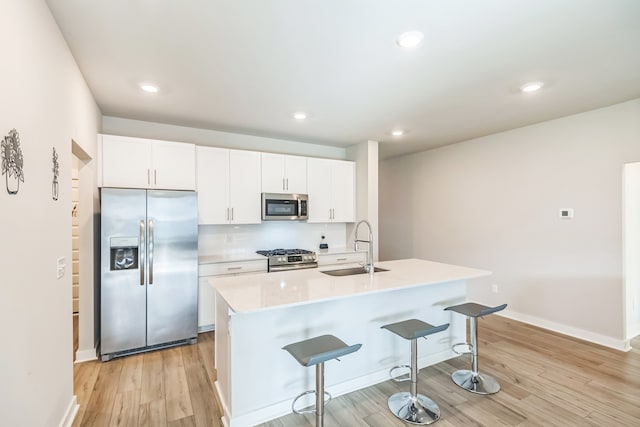 kitchen with a kitchen island with sink, sink, stainless steel appliances, and white cabinets