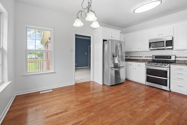 kitchen with appliances with stainless steel finishes, white cabinetry, and light hardwood / wood-style flooring