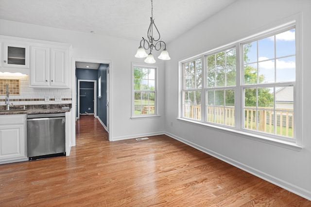 kitchen featuring a healthy amount of sunlight, decorative backsplash, white cabinetry, and dishwasher