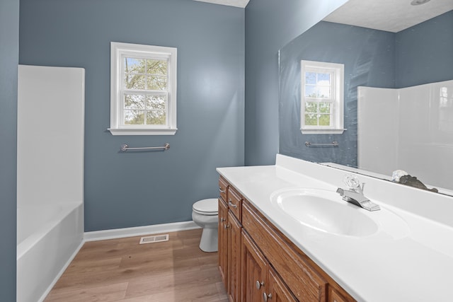 bathroom with wood-type flooring, vanity, plenty of natural light, and toilet