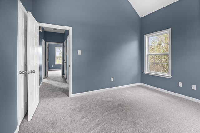 unfurnished room with light colored carpet and lofted ceiling