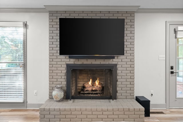 details featuring a brick fireplace, wood-type flooring, and crown molding