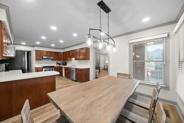 interior space featuring appliances with stainless steel finishes, kitchen peninsula, ornamental molding, and exhaust hood