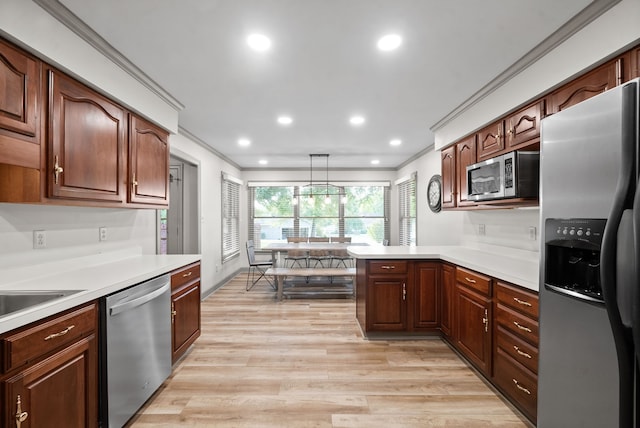 kitchen featuring light hardwood / wood-style floors, kitchen peninsula, pendant lighting, stainless steel appliances, and crown molding