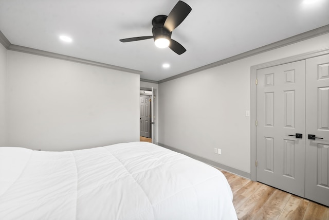 bedroom with ceiling fan, ornamental molding, light wood-type flooring, and a closet