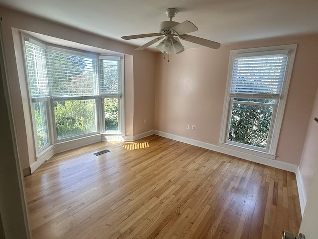 unfurnished room featuring light wood-type flooring, ceiling fan, and plenty of natural light