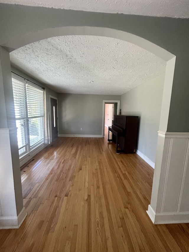 unfurnished living room featuring a textured ceiling and wood-type flooring