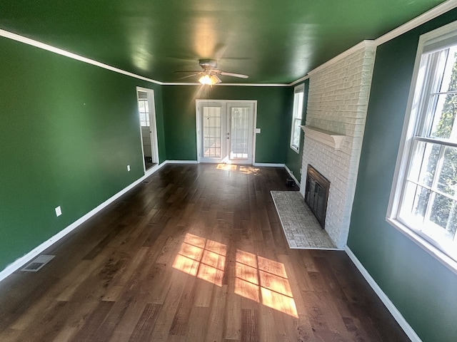 unfurnished living room with a brick fireplace, crown molding, dark wood-type flooring, and ceiling fan