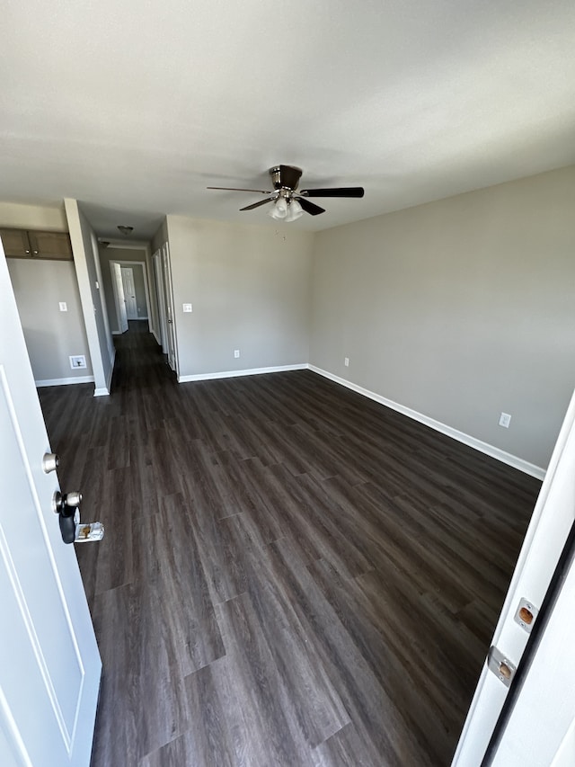 unfurnished living room featuring ceiling fan and dark wood-type flooring