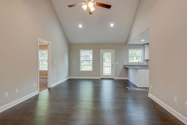 unfurnished living room featuring ceiling fan, sink, dark hardwood / wood-style flooring, and high vaulted ceiling