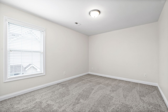 spare room featuring carpet flooring and baseboards