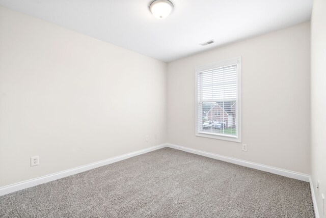 unfurnished room featuring carpet, visible vents, and baseboards