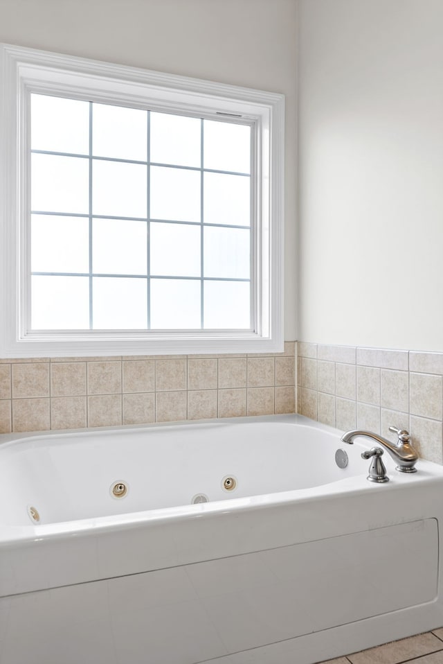 bathroom featuring a jetted tub and plenty of natural light