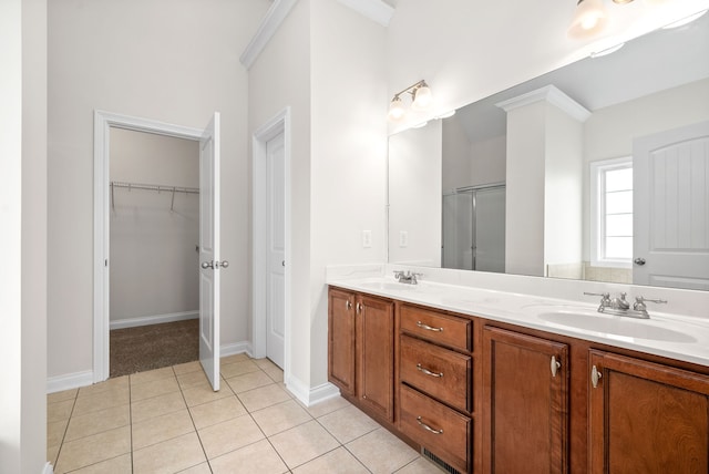 bathroom featuring double vanity, a stall shower, tile patterned flooring, a spacious closet, and a sink