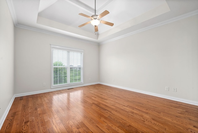 unfurnished room featuring wood finished floors, a ceiling fan, baseboards, ornamental molding, and a raised ceiling