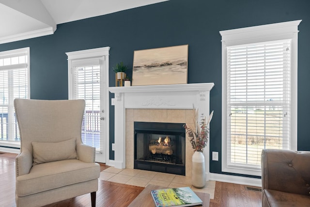 living room with a fireplace, ornamental molding, vaulted ceiling, and hardwood / wood-style flooring