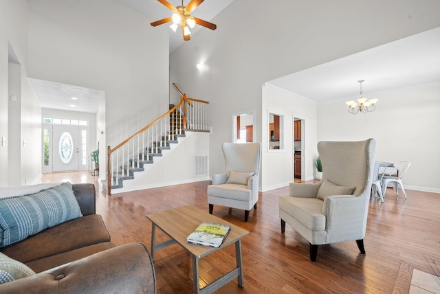 living room featuring hardwood / wood-style floors, a towering ceiling, and ceiling fan with notable chandelier