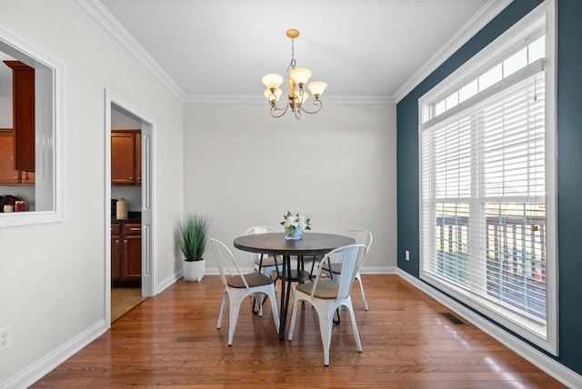 dining space featuring wood-type flooring, ornamental molding, and a chandelier