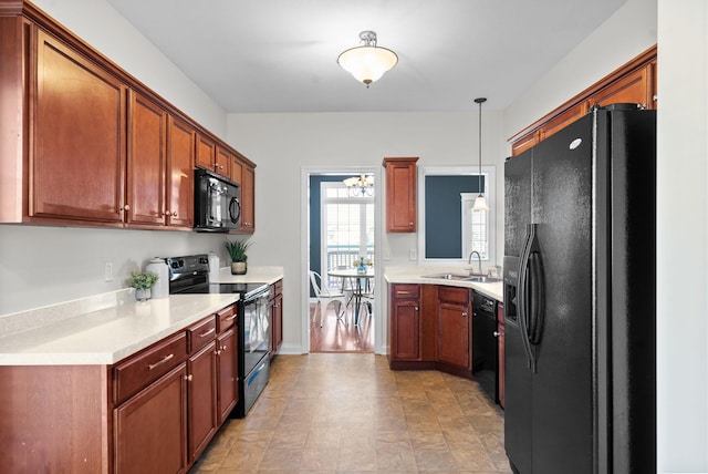 kitchen with brown cabinetry, hanging light fixtures, light countertops, black appliances, and a sink