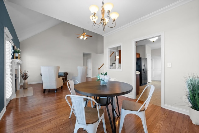 dining room with baseboards, lofted ceiling, stairway, wood finished floors, and a fireplace