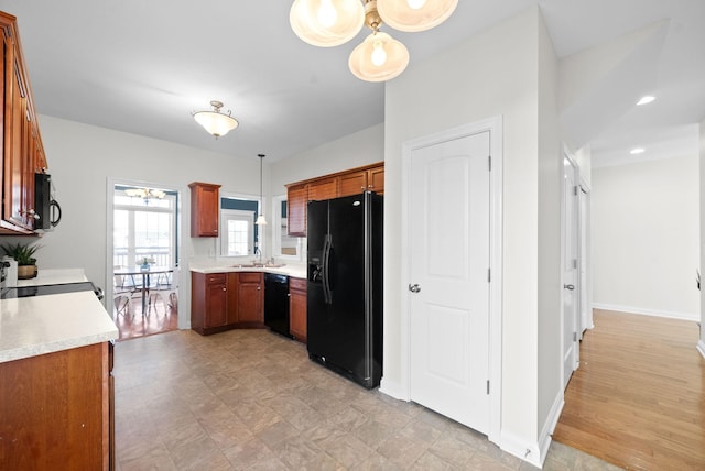 kitchen with black appliances, brown cabinetry, light countertops, and pendant lighting