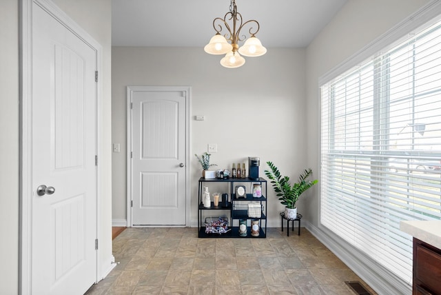 interior space with a chandelier, visible vents, and baseboards