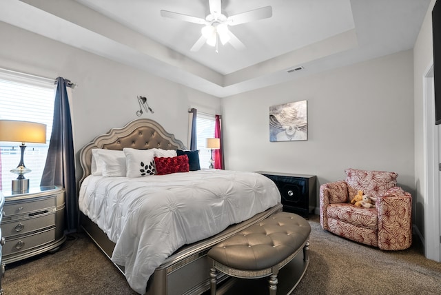 bedroom featuring a tray ceiling, ceiling fan, and dark carpet