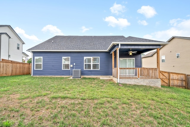 rear view of property featuring ceiling fan, cooling unit, and a yard