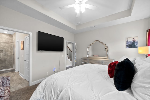 carpeted bedroom featuring a tray ceiling and ceiling fan