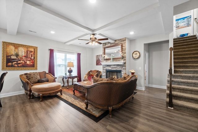 living room featuring beamed ceiling, dark wood-type flooring, coffered ceiling, a stone fireplace, and ceiling fan