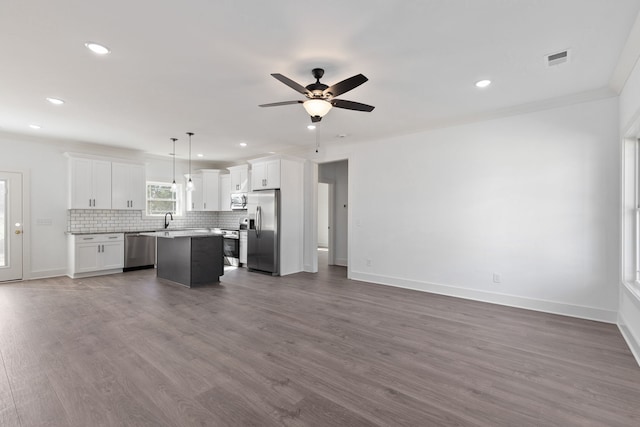 kitchen with pendant lighting, a kitchen island, dark wood-type flooring, white cabinetry, and stainless steel appliances