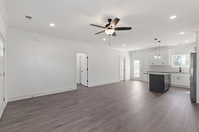 unfurnished living room featuring ceiling fan, dark hardwood / wood-style floors, and crown molding