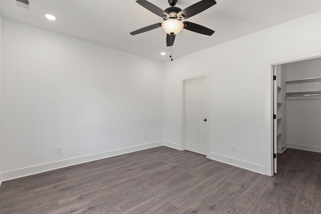 unfurnished bedroom featuring dark hardwood / wood-style flooring, ceiling fan, a walk in closet, and a closet