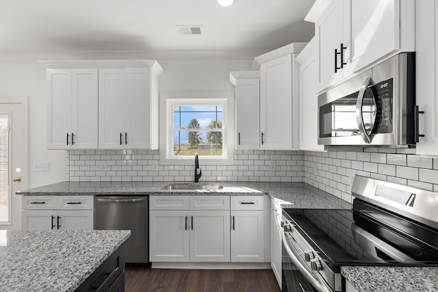 kitchen featuring light stone countertops, white cabinetry, appliances with stainless steel finishes, and sink