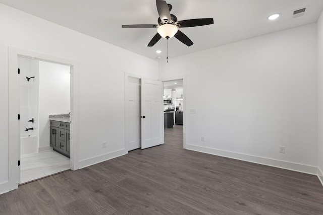 unfurnished bedroom featuring ceiling fan, stainless steel fridge, ensuite bath, and dark hardwood / wood-style floors